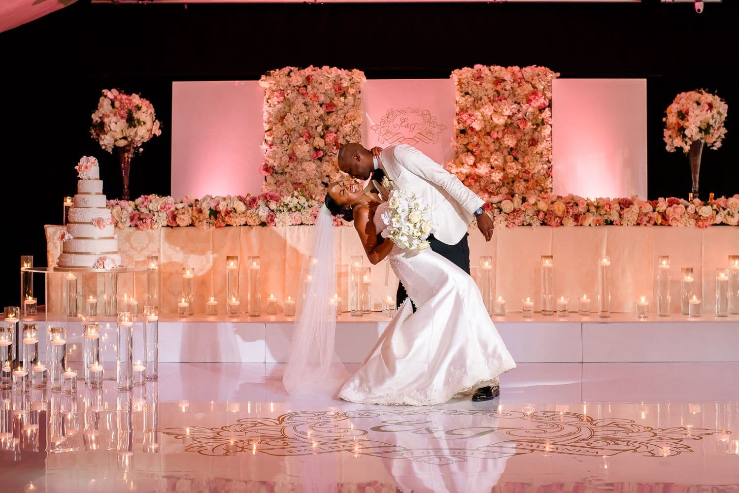 Bride and groom embracing in golden light beneath a flowing veil